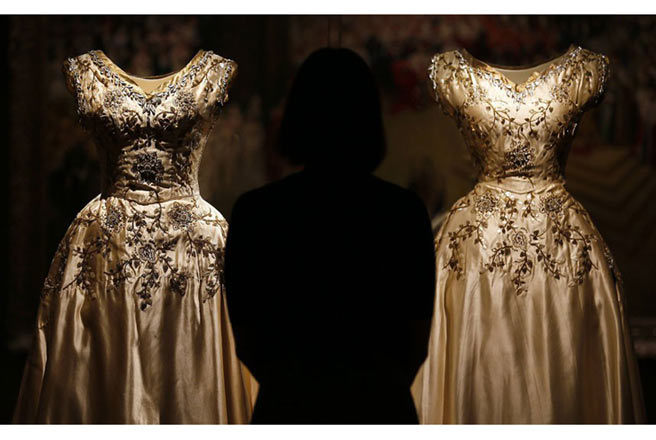 Một khách thăm quan đang ngắm hai chiếc váy của hai thị nữ theo hầu Elizabeth II. Ảnh: Stefan Wermuth