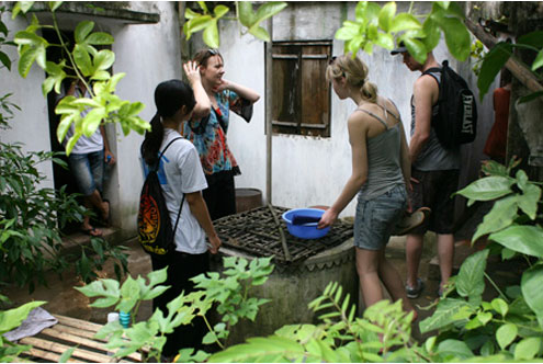 Các khách tham quan đang quan sát chiếc giếng khơi của người Việt.
