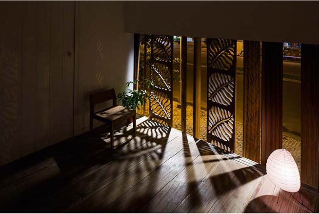 Hệ thống những bản cửa quay trước mặt và sau lưng nhà giữ cho trong nhà được riêng tư mà vẫn điều chỉnh được độ sáng. Những cánh cửa này có trang trí họa tiết lá. 